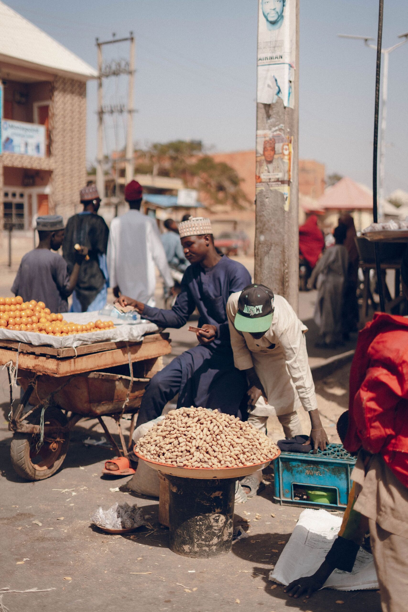 Home Lively street market in Africa with vendors selling fruits and peanuts.