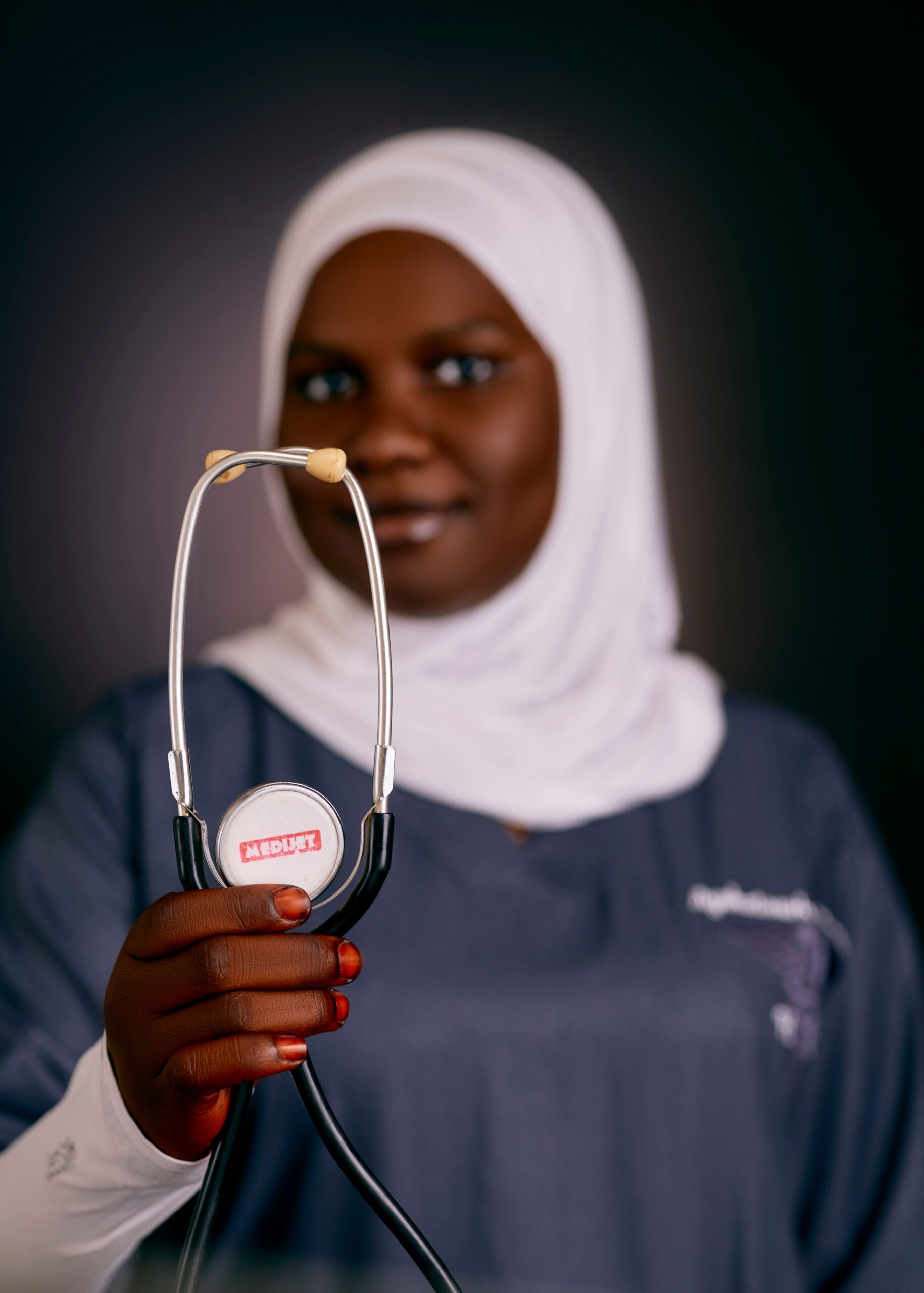 Home African female doctor in hijab holding a stethoscope, emphasizing health care.